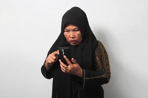 conmocionado medio Envejecido asiático mujer vistiendo hijab reaccionando especial oferta en móvil teléfono foto