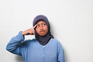 Thoughtful young Asian girl in hijab is thinking with smiling face photo