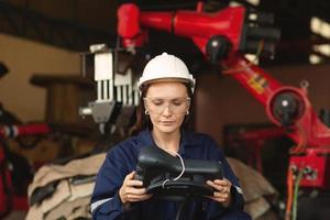 A beautiful engineer controls an automated robotic arm in a smart factory. Welding robots in industrial plants. photo