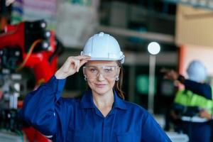 A beautiful engineer controls an automated robotic arm in a smart factory. Welding robots in industrial plants. photo