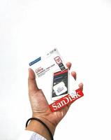 Jakarta, Indonesia in March 2023. Isolated white photo of a hand holding a brand new Sandisk Ultra micro sd memory card