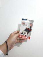 Jakarta, Indonesia in March 2023. Isolated white photo of a hand holding a brand new Sandisk Ultra micro sd memory card