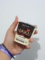 Jakarta, Indonesia in March 2023. Isolated white photo of a hand with a purple blackpink concert wristband bracelet holding a Haku ice cream, one of the ice cream products produced by Glico Wings.