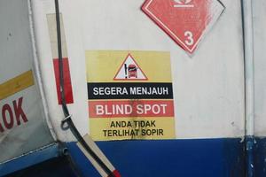 A warning sign for a fuel tank, namely immediately away from BLIND SPOT you are not visible to the driver. photo