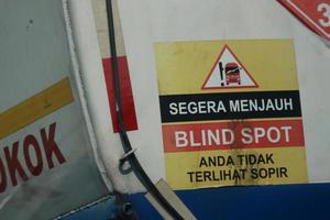 A warning sign for a fuel tank, namely immediately away from BLIND SPOT you are not visible to the driver. photo