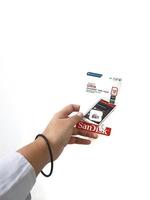 Jakarta, Indonesia in March 2023. Isolated white photo of a hand holding a brand new Sandisk Ultra micro sd memory card