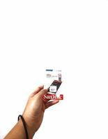 Jakarta, Indonesia in March 2023. Isolated white photo of a hand holding a brand new Sandisk Ultra micro sd memory card