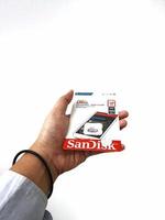 Jakarta, Indonesia in March 2023. Isolated white photo of a hand holding a brand new Sandisk Ultra micro sd memory card