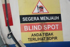 A warning sign for a fuel tank, namely immediately away from BLIND SPOT you are not visible to the driver. photo