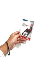 Jakarta, Indonesia in March 2023. Isolated white photo of a hand holding a brand new Sandisk Ultra micro sd memory card