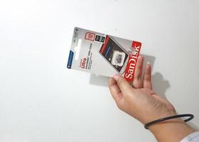 Jakarta, Indonesia in March 2023. Isolated white photo of a hand holding a brand new Sandisk Ultra micro sd memory card