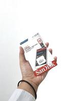 Jakarta, Indonesia in March 2023. Isolated white photo of a hand holding a brand new Sandisk Ultra micro sd memory card