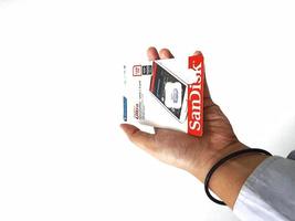 Jakarta, Indonesia in March 2023. Isolated white photo of a hand holding a brand new Sandisk Ultra micro sd memory card