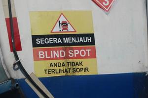 A warning sign for a fuel tank, namely immediately away from BLIND SPOT you are not visible to the driver. photo