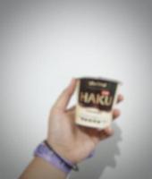 Jakarta, Indonesia in March 2023. Isolated white photo of a hand with a purple blackpink concert wristband bracelet holding a Haku ice cream, one of the ice cream products produced by Glico Wings.