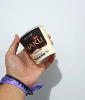 Jakarta, Indonesia in March 2023. Isolated white photo of a hand with a purple blackpink concert wristband bracelet holding a Haku ice cream, one of the ice cream products produced by Glico Wings.