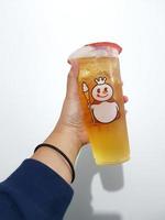 Bekasi, Indonesia in March 2023. Isolated white photo of a hand holding a cup of early grey Mixue tea.