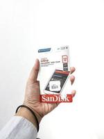 Jakarta, Indonesia in March 2023. Isolated white photo of a hand holding a brand new Sandisk Ultra micro sd memory card