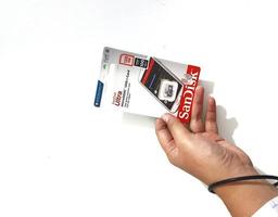 Jakarta, Indonesia in March 2023. Isolated white photo of a hand holding a brand new Sandisk Ultra micro sd memory card