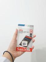 Jakarta, Indonesia in March 2023. Isolated white photo of a hand holding a brand new Sandisk Ultra micro sd memory card