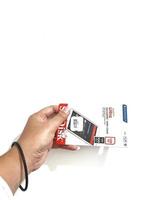 Jakarta, Indonesia in March 2023. Isolated white photo of a hand holding a brand new Sandisk Ultra micro sd memory card