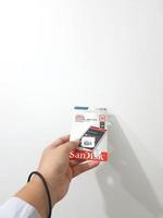 Jakarta, Indonesia in March 2023. Isolated white photo of a hand holding a brand new Sandisk Ultra micro sd memory card