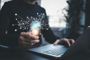 Man working and holding light bulb on the desk, Idea, innovation, and inspiration concept, creativity with hand draw light bulbs that shine glitter, new ideas with innovative technology and creativity photo