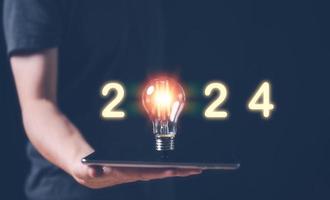 new year business plan and strategy for 2024, man holding glowing lightbulb with 2024 number for creative thinking idea for start new business concept. photo