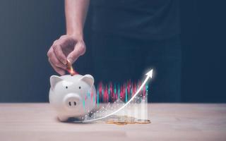 saving investment plan, save for life concept, man putting coin in to piggybank and virtual trading graph, photo