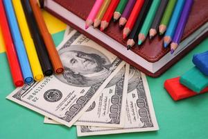 Pens, colored pencils, plasticine, book, hundred dollar bills photo