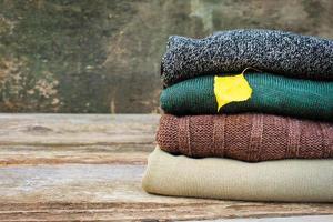 Pile of colorful warm clothes on wooden background. Toned image. photo