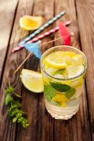 Drink with lemon, mint, ice, water on wooden background. Toned image photo