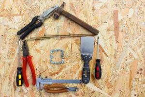 Construction tools in the form of house on wooden background. photo