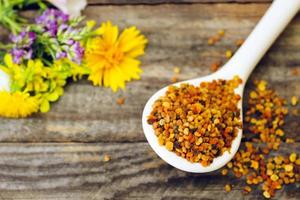 Bee pollen and field flowers on old wooden background. Toned image. photo