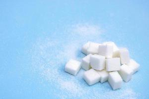 white sugar in cubes on a blue background with copy space, culinary background photo