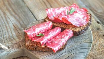 sándwiches con salami en el tablero de madera foto