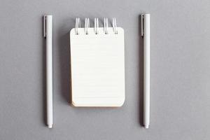 Top view of blank note paper with pen on gray background photo