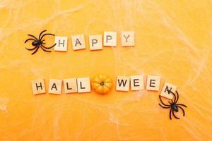 the inscription happy halloween with spider web and spiders on orange background photo