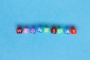 inscription wednesday made by multicolor plastic cubes on a blue background. photo