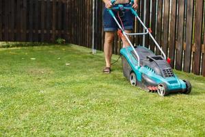 a man mows a lawn with a lawn mower photo