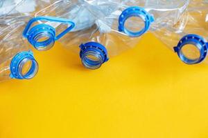 a lot of plastic empty rumpled used bottles on a yellow background. waste and pollution concept photo