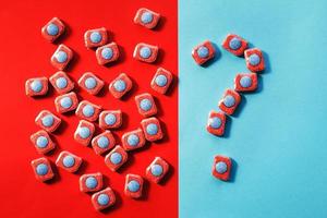 capsules for kitchen dishwashers and a question mark on a blue and red background. flat lay. photo