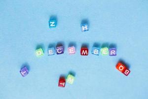 inscription december made by multicolor plastic cubes on a blue background. photo