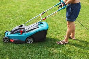 a man mows a lawn with a lawn mower photo
