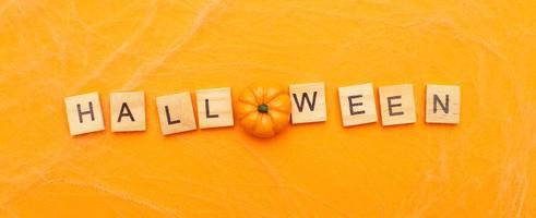 the inscription halloween sale with little pumpkin on orange background with spider web. banner photo
