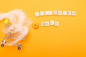 shopping cart with spider web and the inscription halloween sale on orange background. photo