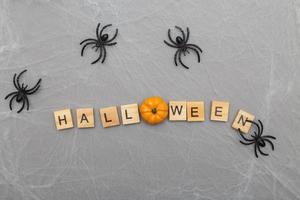 the inscription halloween with spider web and spiders on a gray background photo