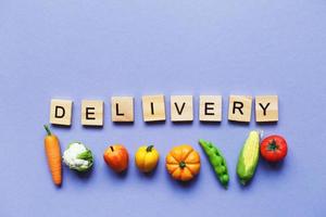 inscription delivery with vegetables and fruits on purple background. delivery service concept photo