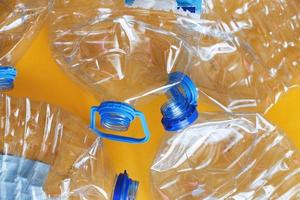 un montón de botellas de plástico vacías y arrugadas sobre un fondo amarillo. concepto de residuos y contaminación foto