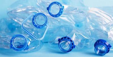 un montón de botellas de plástico vacías y arrugadas sobre un fondo azul. concepto de residuos y contaminación foto
